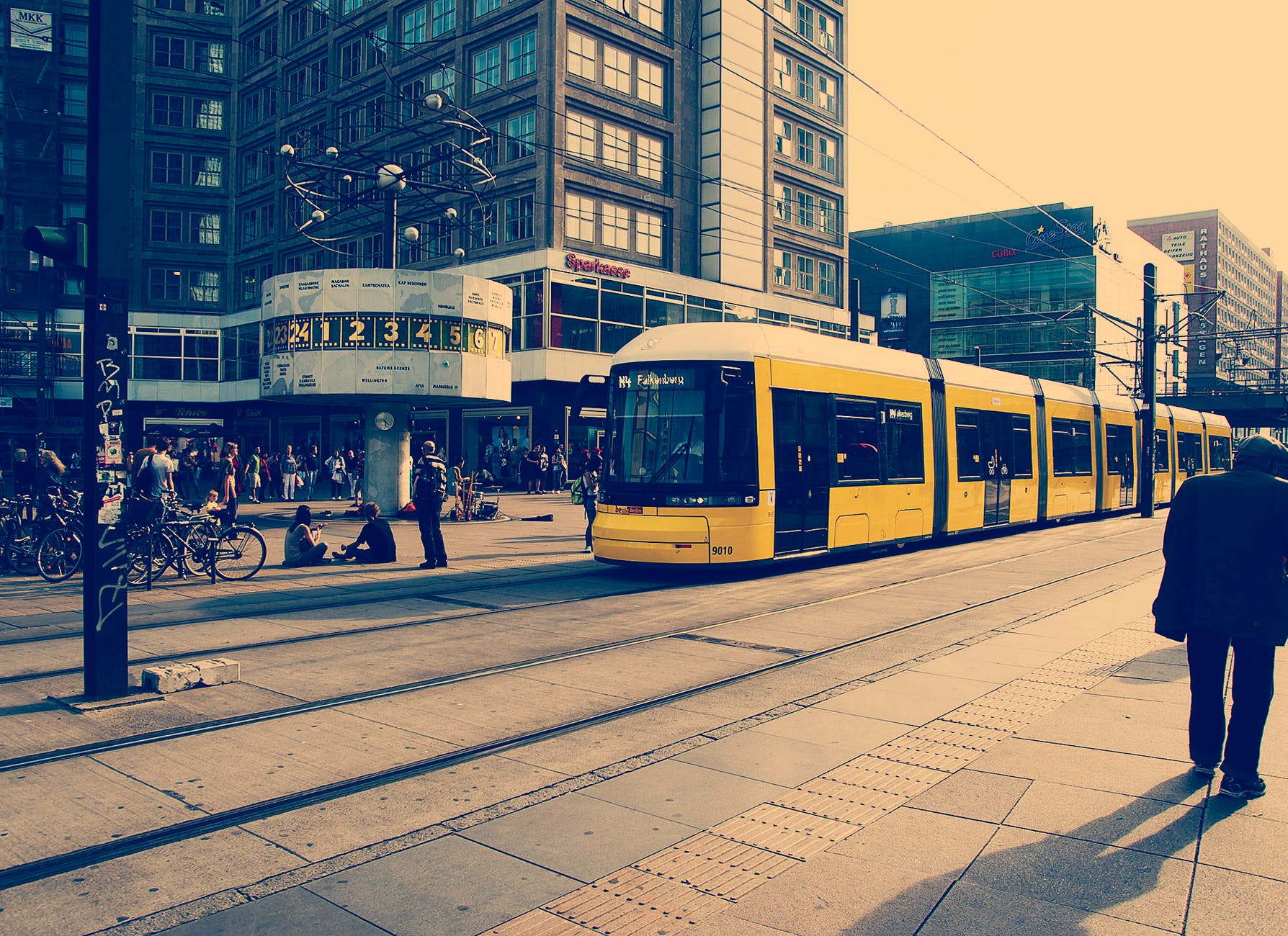 selective color photography of yellow train near concrete buildings